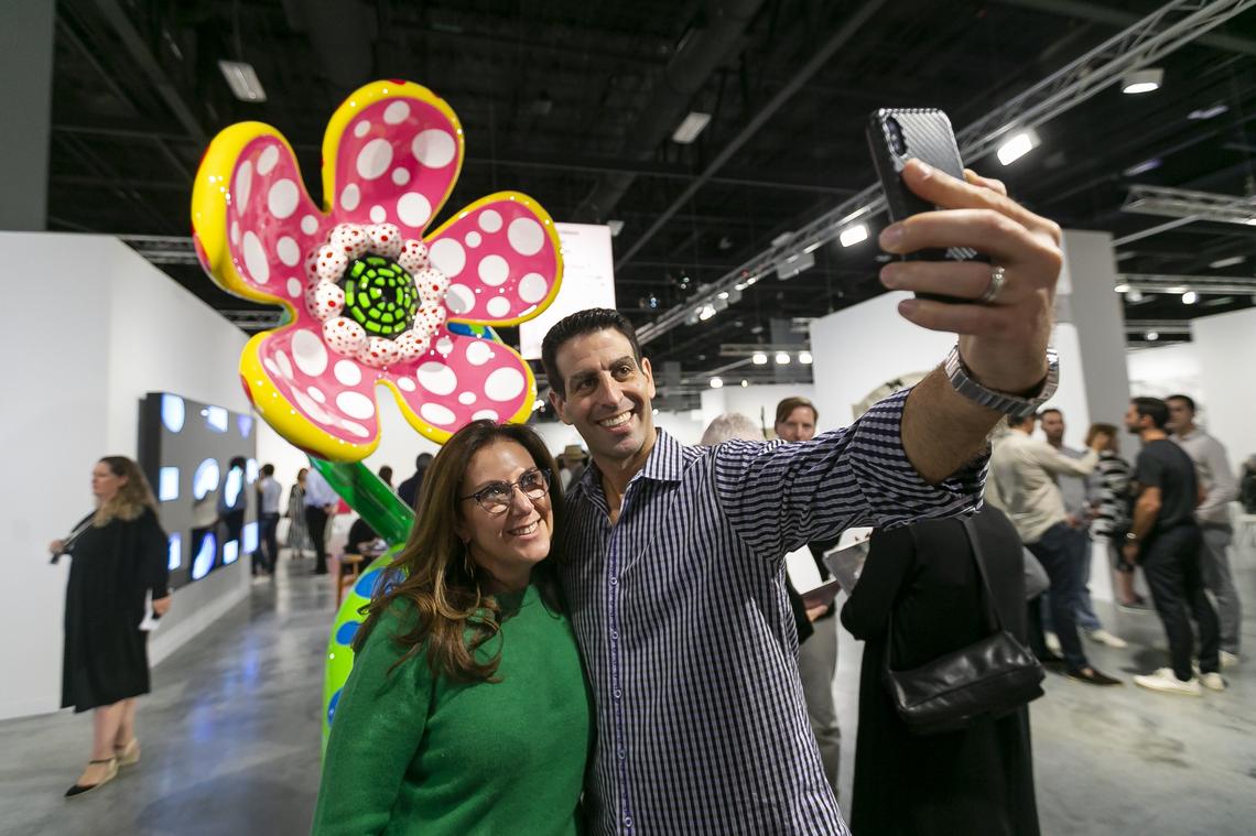 Michele Scheck and her husband, Steven Scheck, take a selfie next to “Flowers that speak all about my heart given to the sky” by Yayoi Kusama during Art Basel at the Miami Beach Convention Center on Wednesday, December 4, 2019.