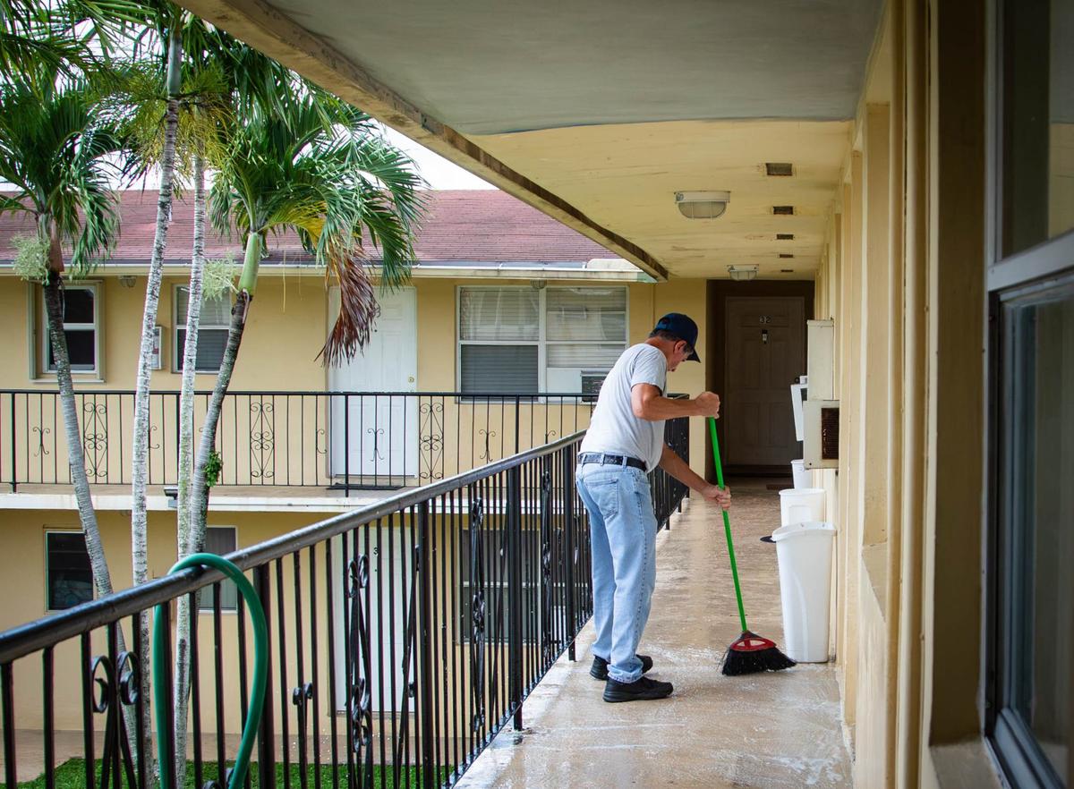 A man who regularly washes the apartment complex floors, cleans in front the apartment of Clifford Renard Murray III and Rosemary Gutierrez on Wednesday, Aug. 28, 2024, in Hialeah, Fla. Murray and Gutierrez were found dead by Hialeah police in the apartment Tuesday night in an apparent murder-suicide.