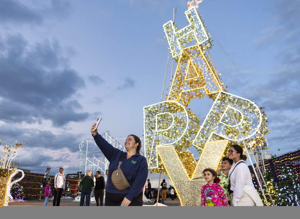 Madelin Perez, left, holds her phone to take a selfie with Amanda Santana, Rene Moris, 9, Isabella Moris, 6, during the grand opening of Ripley's Believe It or Not! Christmas Park at Amelia Earhart Park on Thursday, Nov. 13, 2025, in Hialeah, Fla.