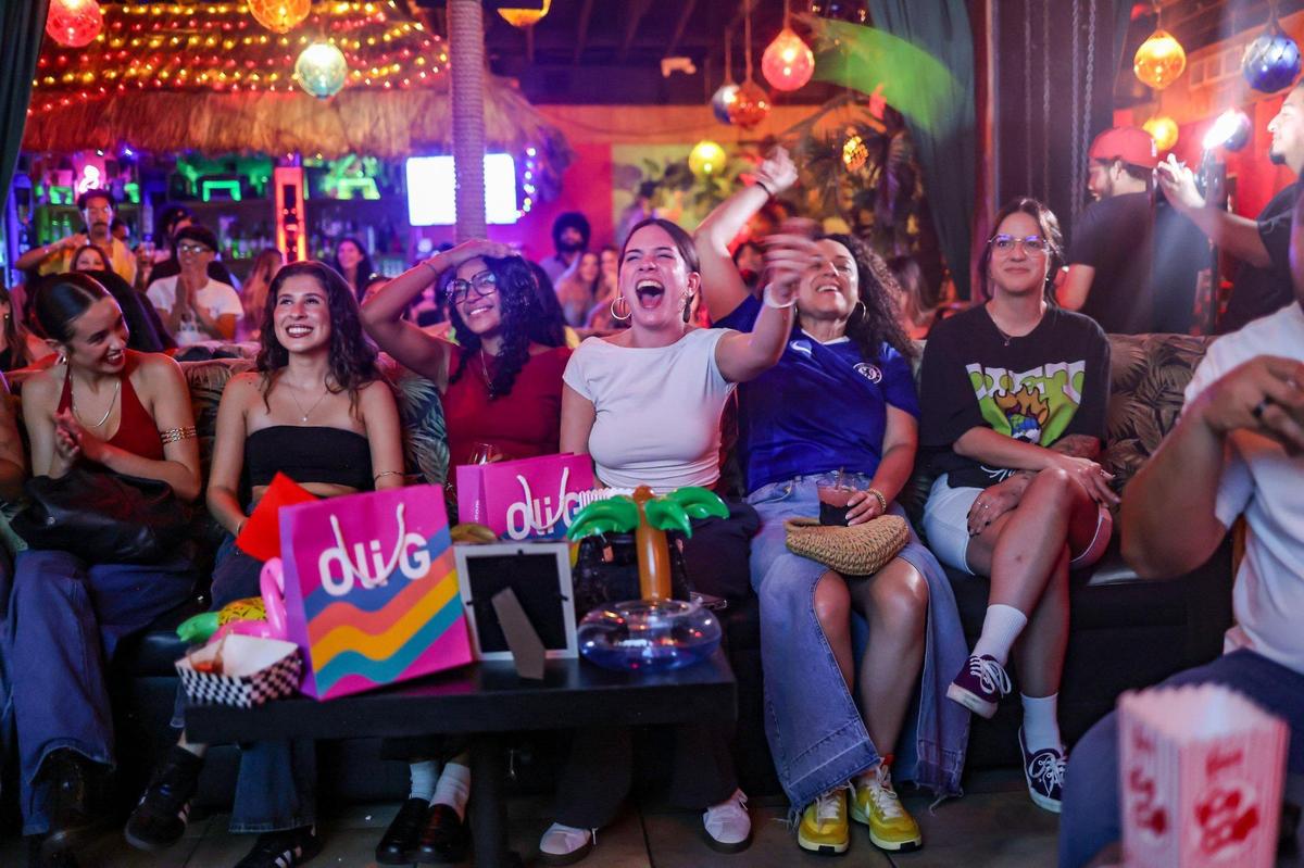 Raysa Rey, 26, center, waves her green flag while watching the “Love Island” finale with friends at The Dead Flamingo in Little Havana on Sunday, July 13, 2025, in Miami, Florida.