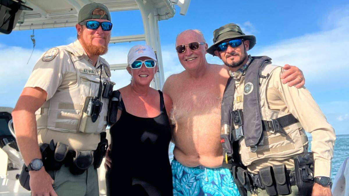 Officers from the Fish and Wildlife Conservation Commission pose with Lawrence Boyts and his wife, Donna, after Lawrence was rescued from the water about a mile from where his boat was anchored on Aug. 12, 2022.