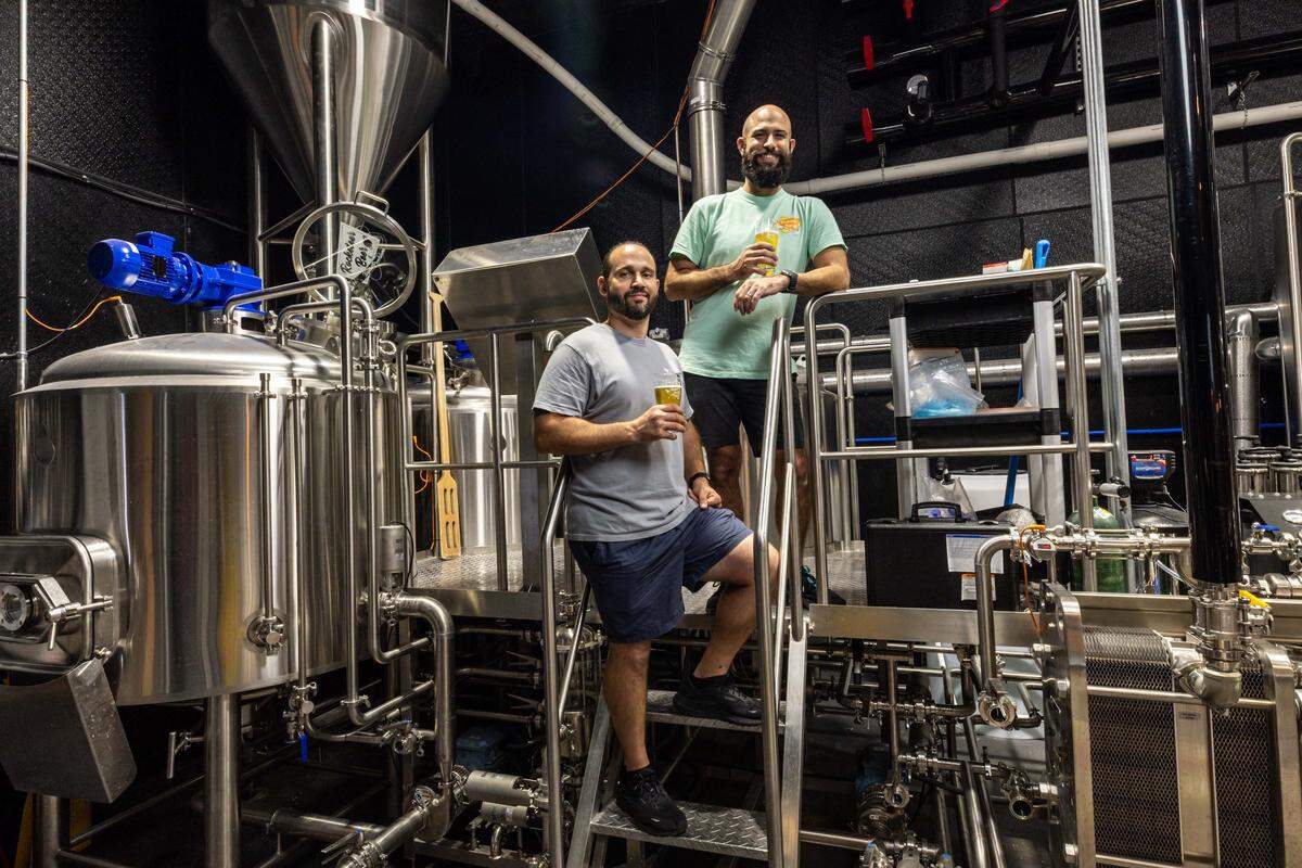 Owners and operators Rick Abreu and Rudy Delgado hold beers as they stand by the brewery inside Rocketeer Beer & Liquid Provisions on Monday, October 13, 2025, in Miami, Fla.