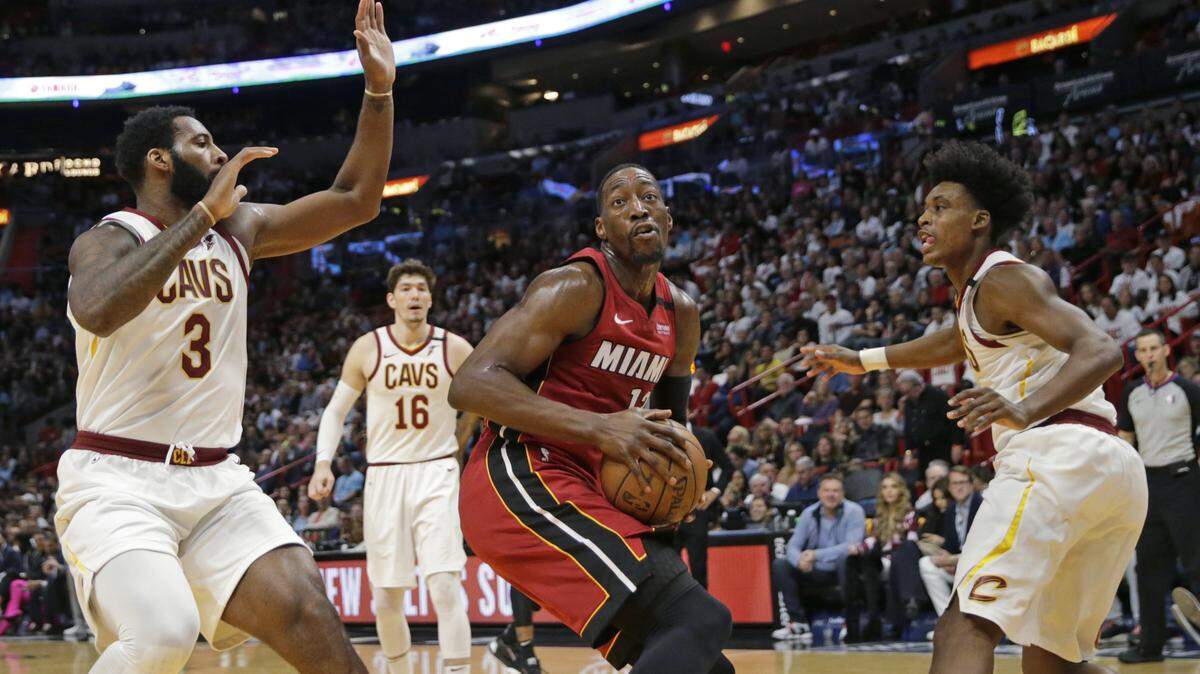 Miami Heat center Bam Adebayo (13) goes to the basket against Cleveland Cavaliers center Andre Drummond (3) and Kevin Porter Jr. (4) in the first quarter of a Feb. 22 game.