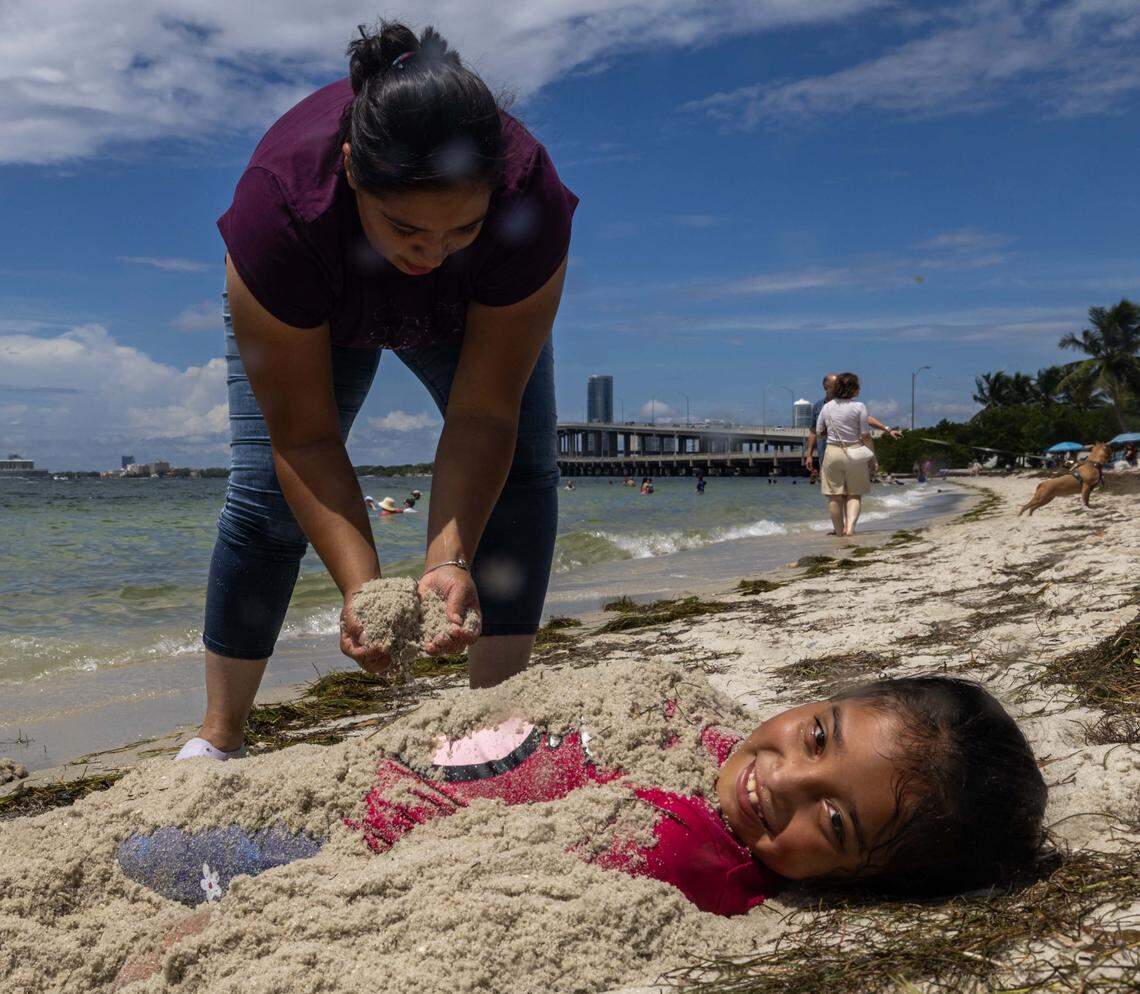 Silvia Lopez, 30, buries her daughter, Fatima, 7, in the sand   at Hobie Island Beach on Monday, September 1, 2025, in Key Biscayne, Fla.