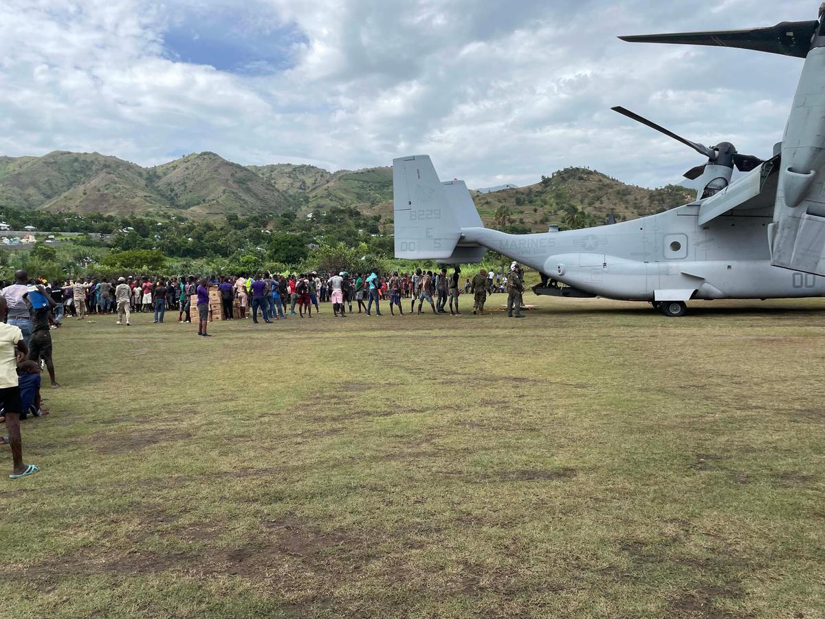 A crowd lines up on Aug. 21, 2021, to welcome a U.S. military aircraft dropping off aid in Les Anglais for victims of the Aug. 14 earthquake. The remote community in southern Haiti was hard hit by the disaster.