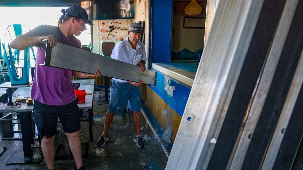 Ft. Myers resident Christopher Boyce Jr, 25, left, assists in the cleanup process at Mr. Wave Island on Fort Myers Beach