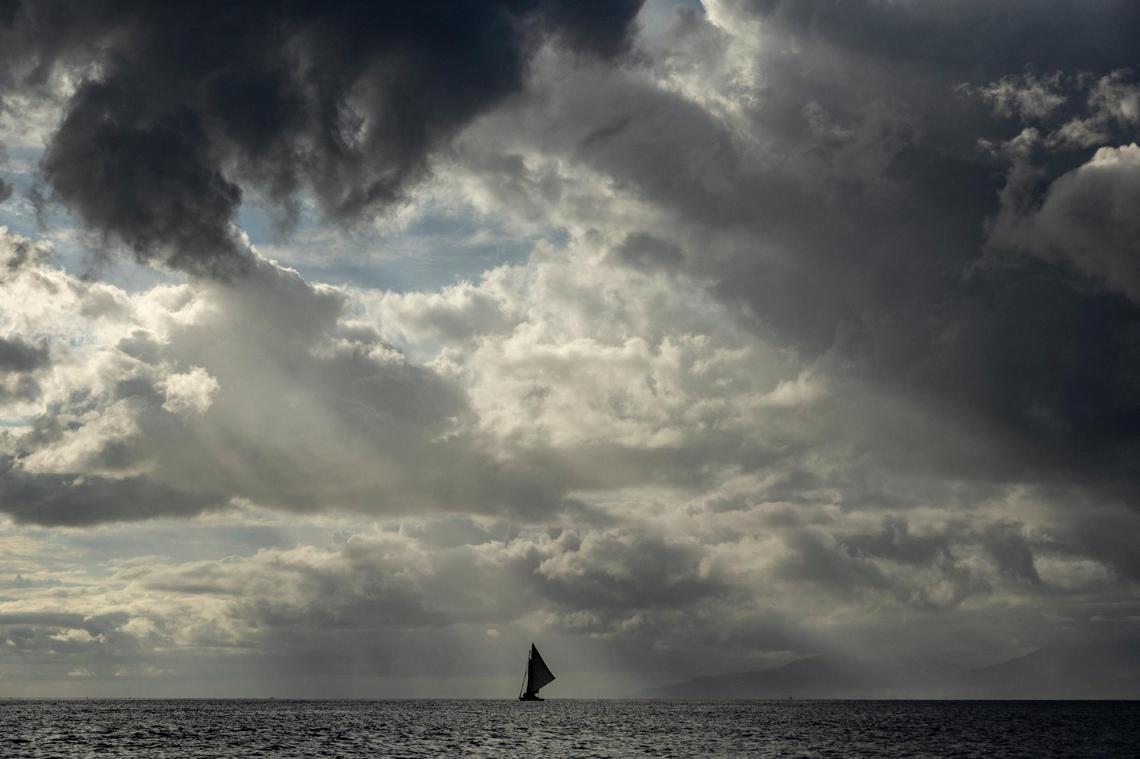A Haitian sailboat makes its way along the Canal de la Tortue separating Île de la Tortue and mainland Haiti, under threatening skies off Haiti’s northwest coast on March 26, 2022.