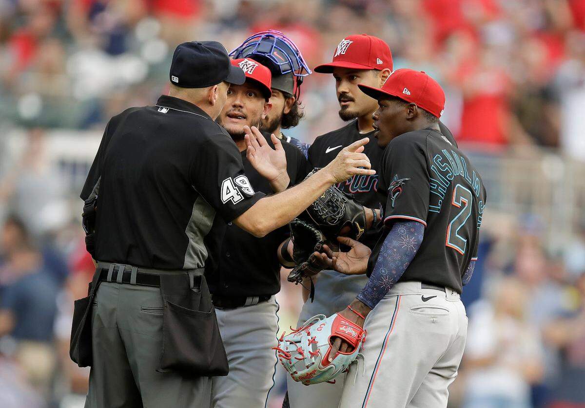 Home plate umpire Andy Fletcher, left, speaks with Miami Marlins pitcher Pablo Lopez, second from right, shortstop Miguel Rojas, second from left, and second baseman Jazz Chisholm Jr. (2) during the first inning of a baseball game against the against the Atlanta Braves on Friday, July 2, 2021, in Atlanta. Lopez and manager Don Mattingly were both ejected. (AP Photo/Ben Margot)