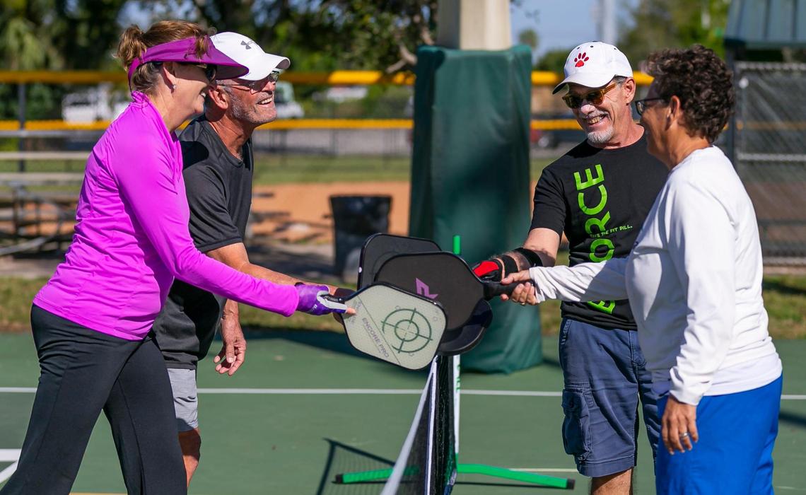 From left to right: Lori Davison, 54, Charlie Bibb, 66, Jose Canovas, 62, and Victoria Luther, 61, celebrate after playing a game of pickleball at Suniland Park in Pinecrest, Florida on Friday, January 14, 2022.