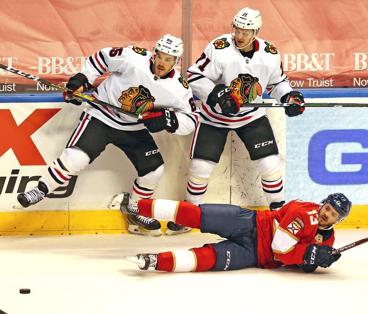 Florida Panthers Vinnie Hinostroza (13) hits the ice after colliding with Chicago Blackhawks Andrew Shaw (65) and Lucas Wallmark (71) at the BB&T Center in Sunrise, Florida, Tuesday, January 19, 2021.