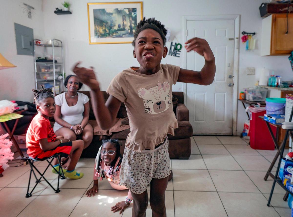 Willnat Young, a single mom of three, watches Amaziah Young jump as she watches television. Joining her in the living room of their Little Haiti home are twin brother Ammiel Young and sister Aaliyah Martin, playing on the floor.
