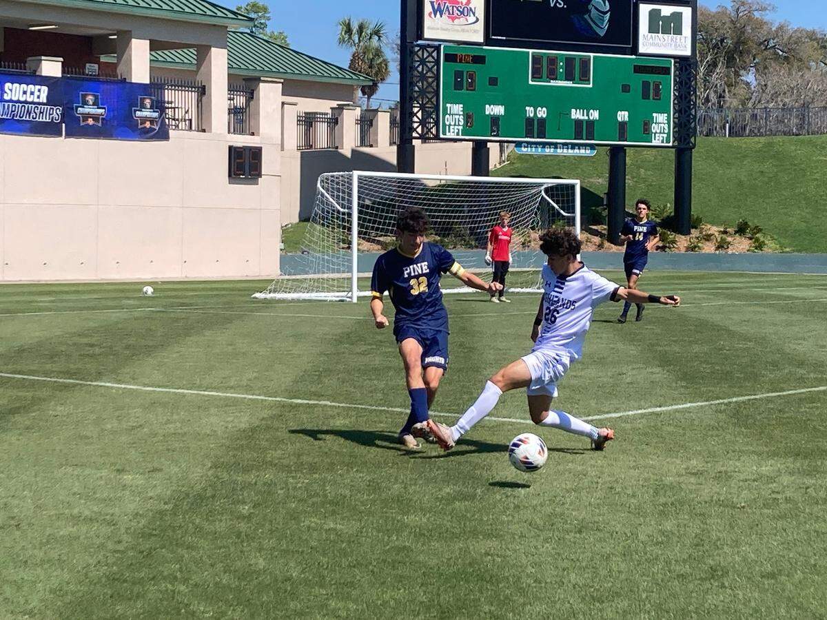 Highlands Christian’s Pablo Bedoya (white jersey) looks to work the ball into Pine School’s 18-yard box during Wednesday’s Class 1A state boys’ soccer semifinal at Spec Martin Stadium in DeLand, Fla.