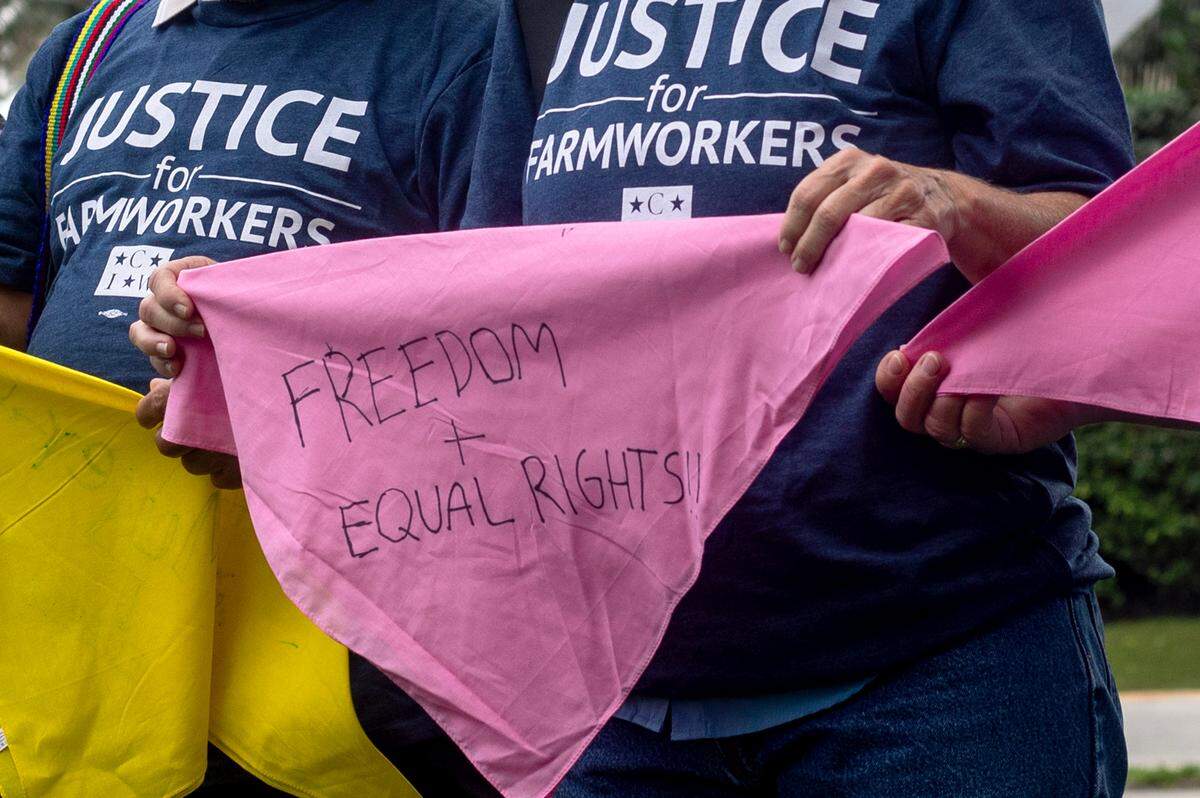 A member of the Coalition of Immokalee Workers holds a bandana that says freedom and equal rights.