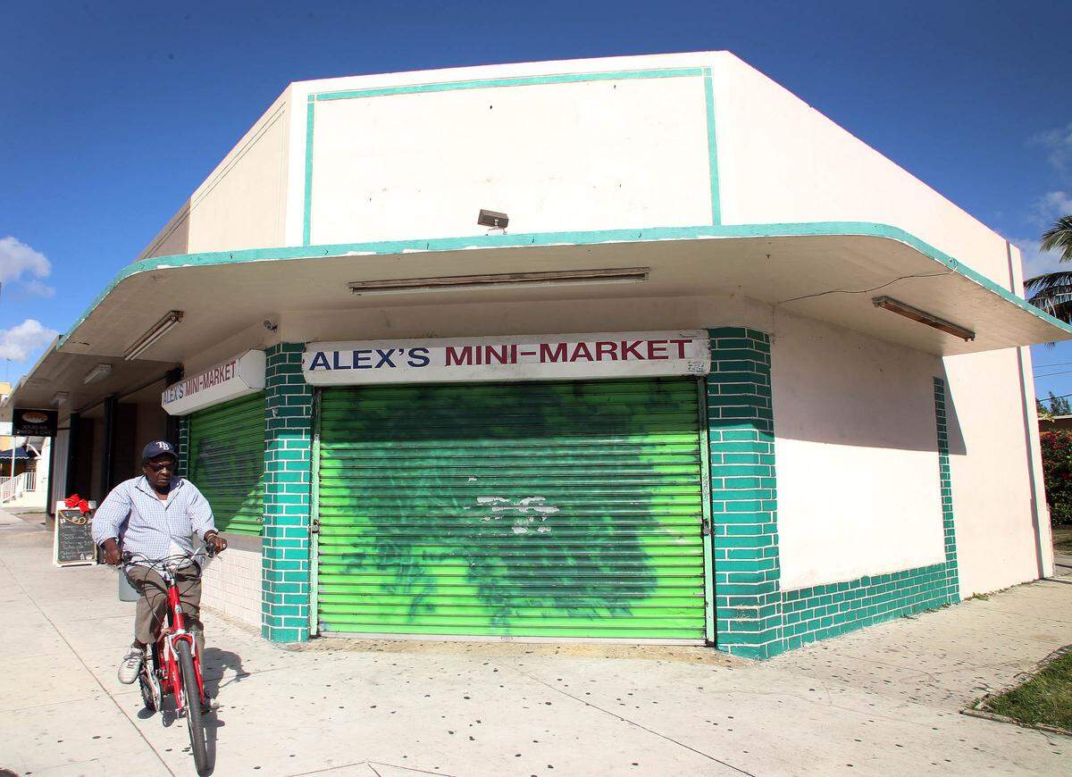 A man bicycles past Alex’s Mini Mart in Miami’s Little Havana neighborhood in December 2011. The owner of the now-defunct business, Yue “Alex” Kui Cen, suffered severe brain damage when an attacker hit him in the head with a hammer.