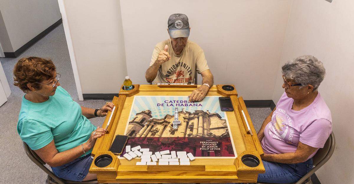 From left- Blanca Rebelled, Jorge Garrido and Maria Esther Salgado play dominoes at the Diener JCS Family Center in Miami Beach, where members received many services including lunch, entertainment, etc all year round that could be affected as JCS is one of over 40 nonprofits that's losing significant funds ($16 million) due to Miami-Dade County budget cuts, on Tuesday, August 12, 2025.