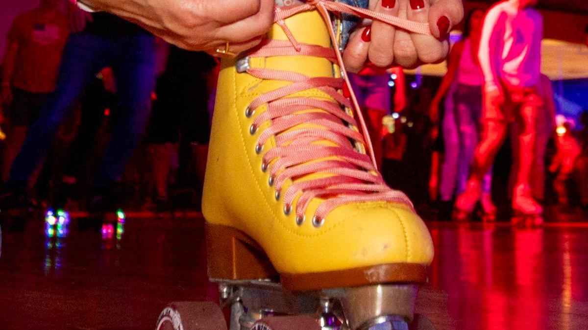 A roller-skater tightens her skates next to the rink during a skating party to mark the official closing of Super Wheels in Miami, Florida, on Saturday, November 25, 2023.