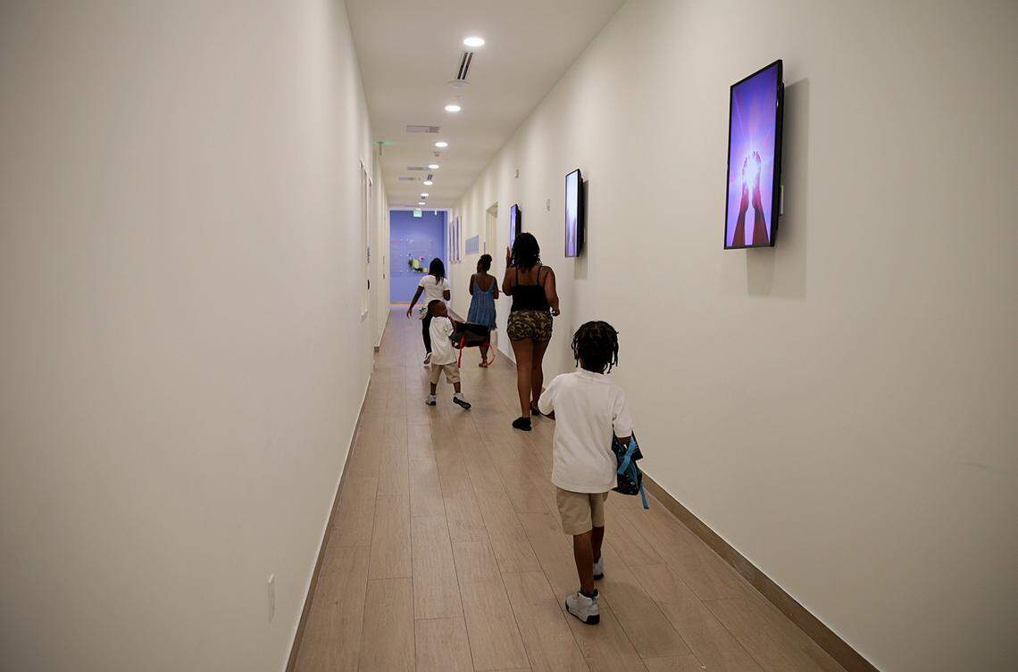 Residents pass by a hallway at the new Lotus House shelter for homeless women and children in Overtown. The $25 million project, which will accommodate 490 women and children, will open on Thursday.