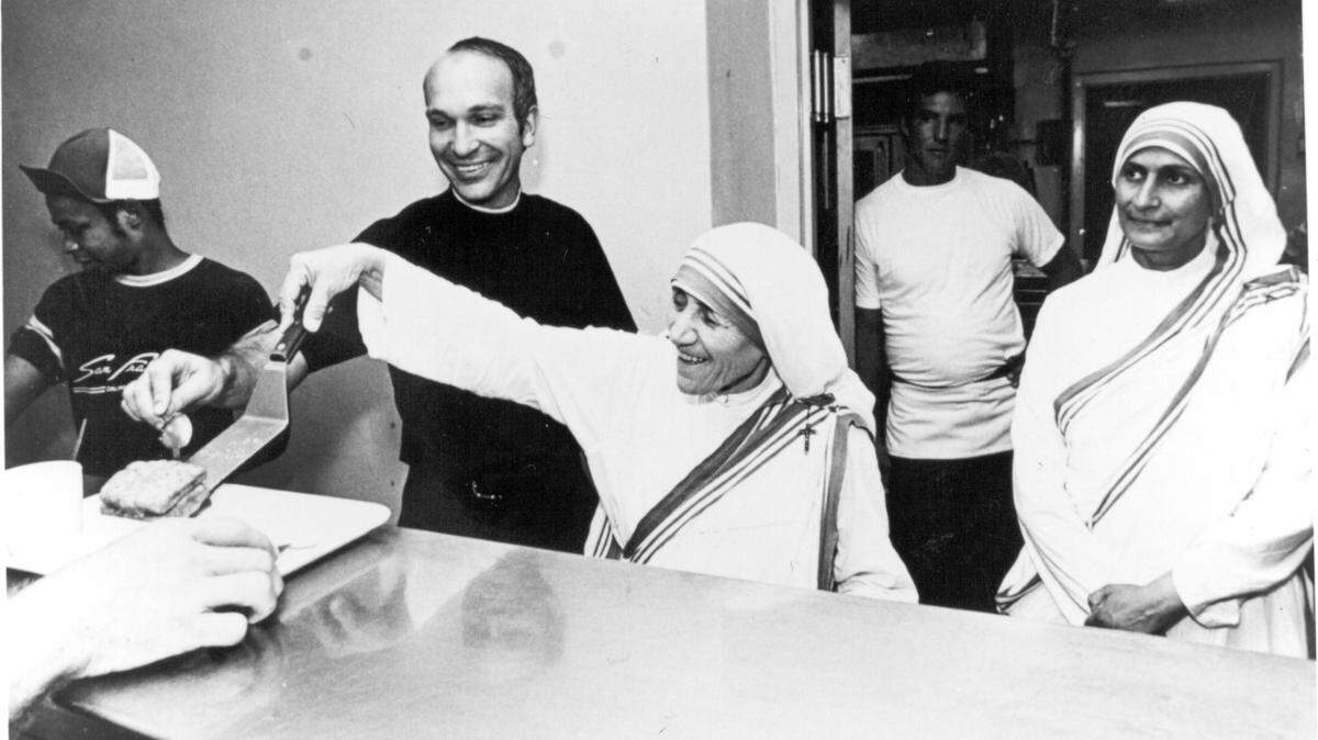 Paul Johnson serves food to the homeless with Mother Teresa of Calcutta at Camillus House in Miami. 