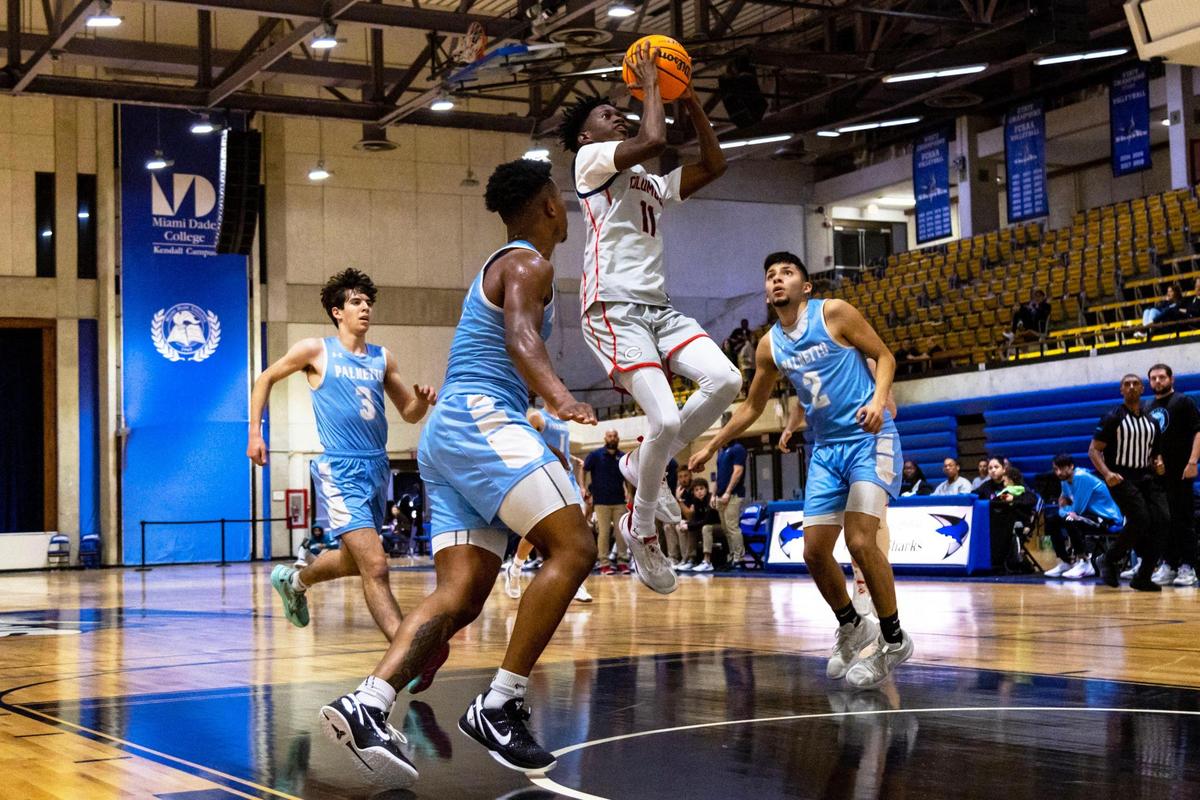 Christopher Columbus High School guard Garyn Bess (11) flies through the lane after dribbling past Miami Palmetto Senior High School defenders Matthew Mairena (2) and Joshua Lipson (3) during the first half of the boys’ GMAC Basketball Finals at Miami-Dade College Kendall campus Gibson Gymnasium in Miami, Florida, on Friday, January 27, 2023.