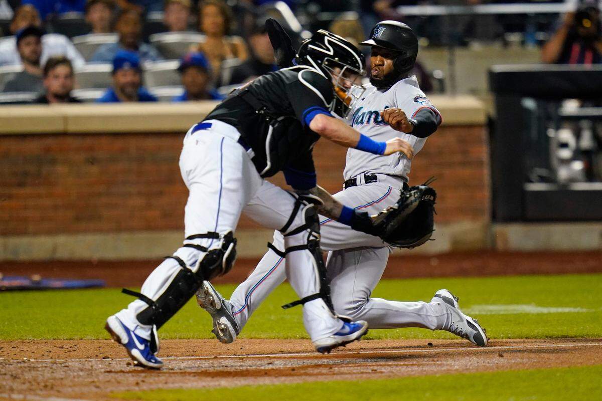 Miami Marlins’ Bryan De La Cruz, right, slides past New York Mets catcher Tomas Nido to score on sacrifice fly by Joey Wendle during the fifth inning of a baseball game Friday, July 8, 2022, in New York. (AP Photo/Frank Franklin II)