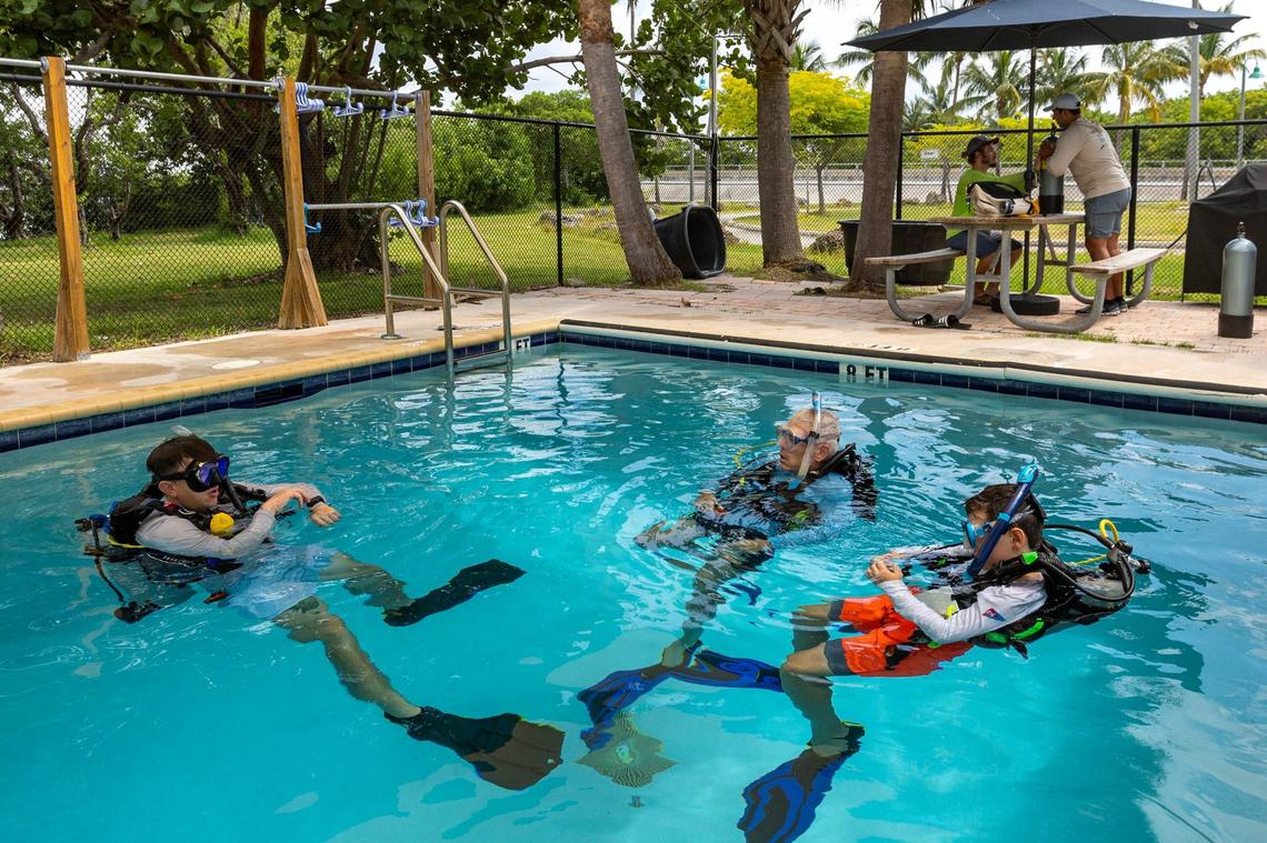 Diver’s Paradise dive instructor Michael Pondel, left, directs Paul Miller, center, and Matteo Miller, 12, right, during a pool session on Thursday, August 8, 2024, in Key Biscayne, Fla.