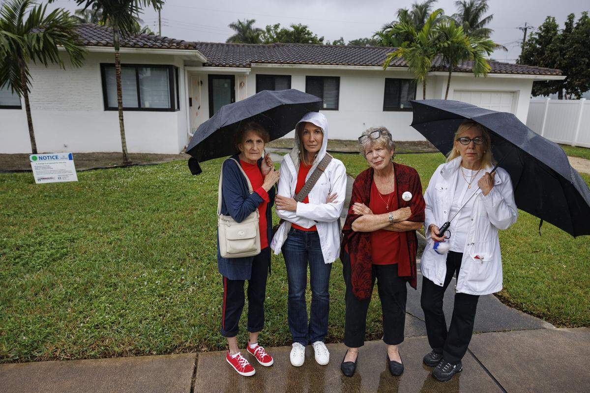 From left to right: Bonnie Hughey, Clover Ryan, spokesperson for the residents, Siobhan McLaughlin, and Vanessa Mercier pose in front of the home in their neighborhood that would be demolished to build a mikvah, Jewish bathhouse, during the day on Tuesday, Dec. 9, 2025, in Hollywood, Fla. The Historic Preservation Board must decide whether to approve a Jewish bathhouse on a residential street situated between single family homes.