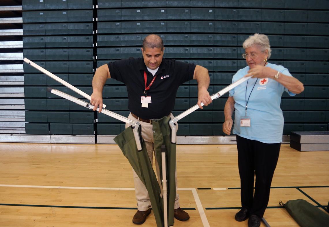 Volunteers Luis Riera, left, and Aurora Galli demonstrate how to assemble a cot for Miami-Dade employees during the Miami-Dade and the American Red Cross training exercises for hurricane preparation inside Ronald Reagan High School's gym in Doral, Florida, on Thursday, June 28, 2018.
