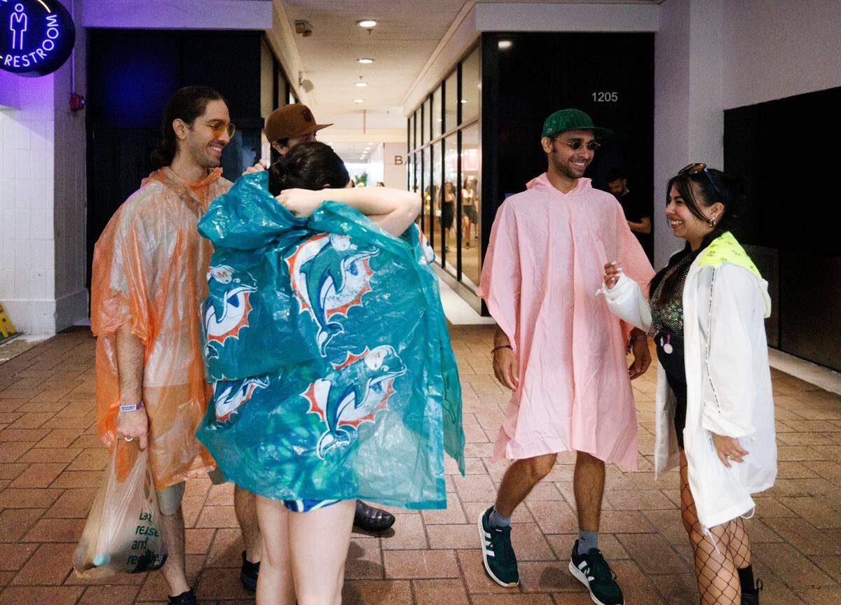 Festival-goers take cover from the rain in the Bayside Marketplace when Ultra shut down their entrances during the third day of Ultra Music Festival on Sunday, March 30, 2025, at Bayfront Park in downtown Miami, Fla. 