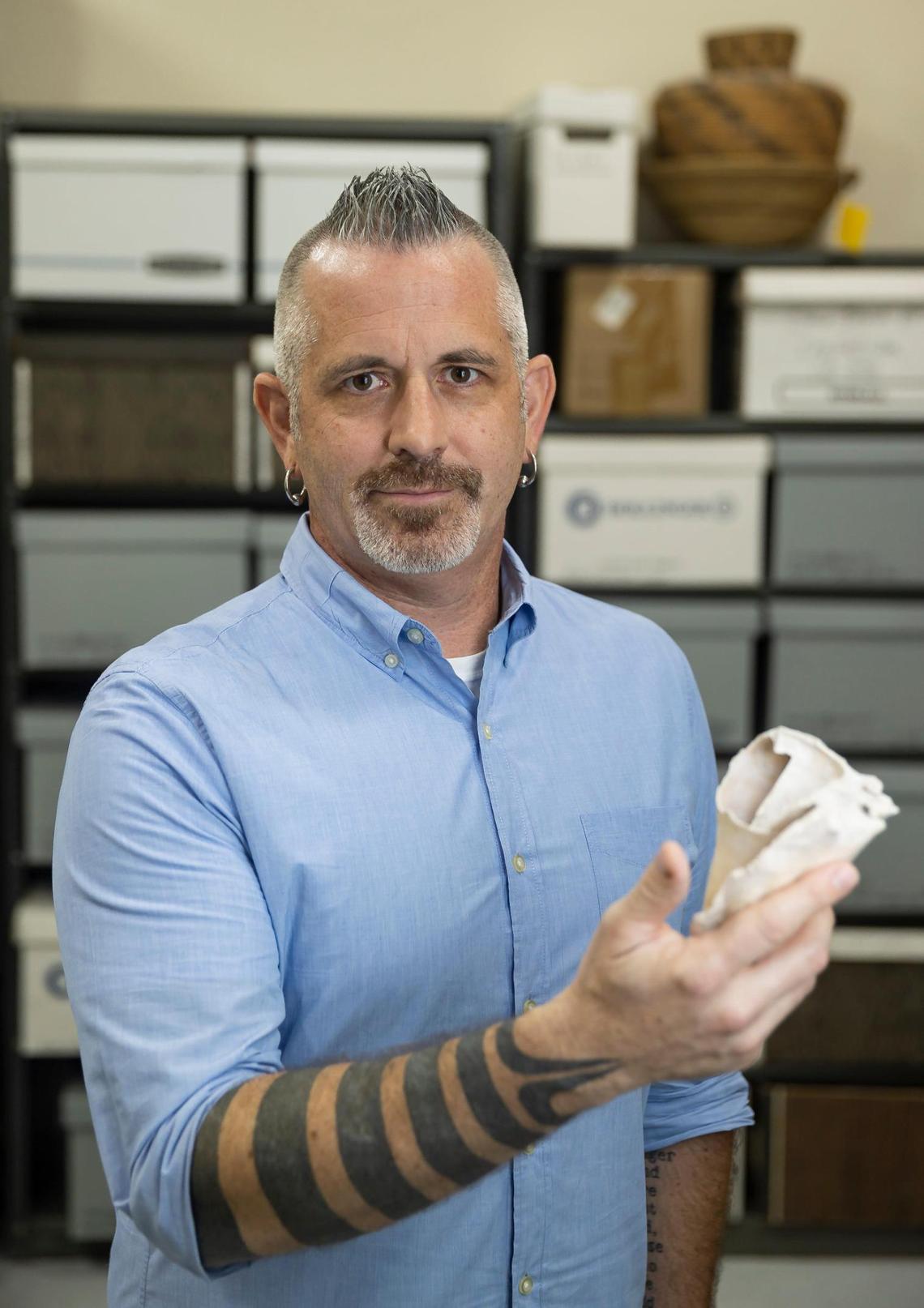 William Pestle, an archaeologist and chairman of anthropology at the University of Miami, is photographed inside his department’s artifact storage room holding a conch shell from a prehistoric archaeological site in the Florida Keys.