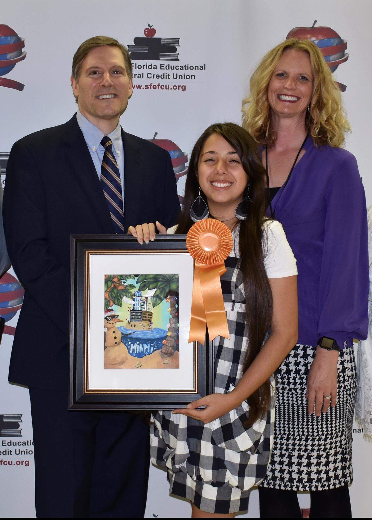 Miami-Dade students and families were celebrated at the annual&nbsp;My Miami Holiday Art Contest winners’ reception. From left, Michael DiBenedetto, SFEFCU President & CEO; Sureily Marestein, My Miami Art Contest Grand Prize Winner; and Janell Upton, SFEFCU Executive Vice-President. 