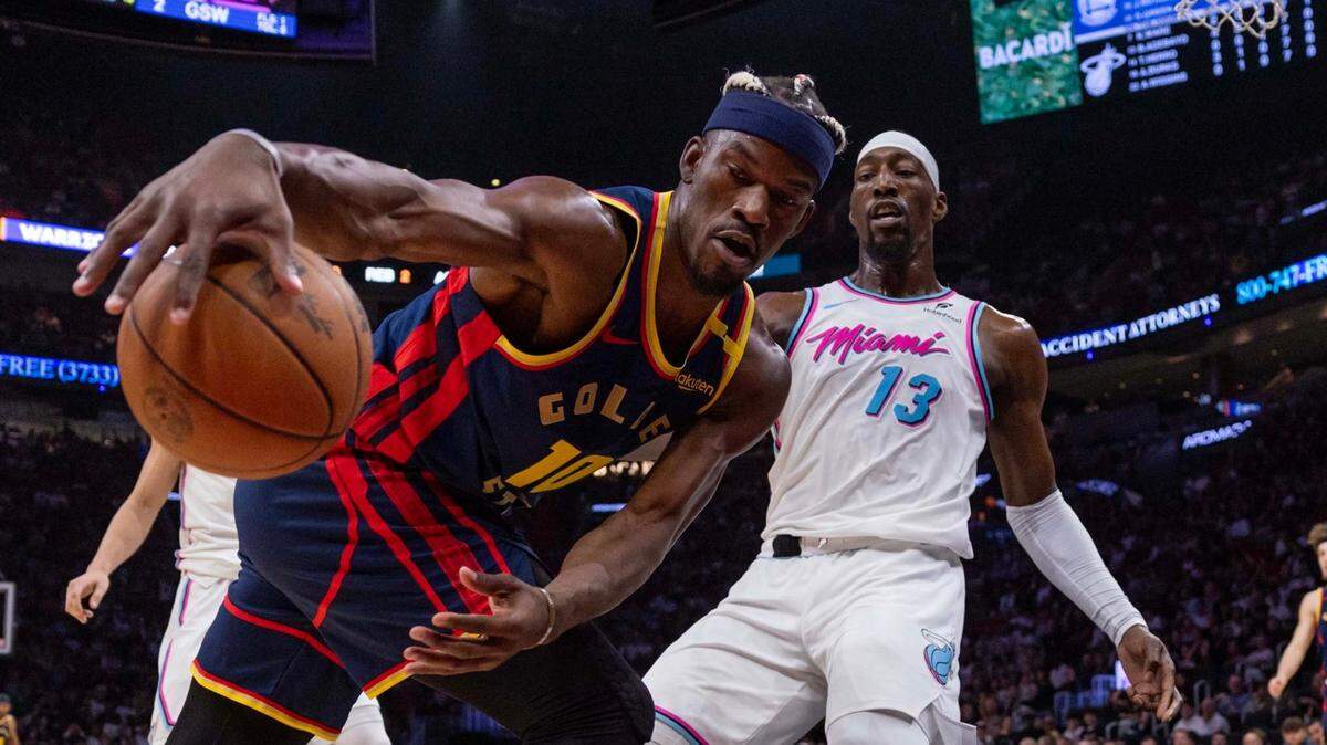 Golden State Warriors forward Jimmy Butler III (10) grabs the loose ball while defended by Miami Heat center Bam Adebayo (13) during the first half of an NBA game at Kaseya Center on Tuesday, March 25, 2025, in Miami, Florida.