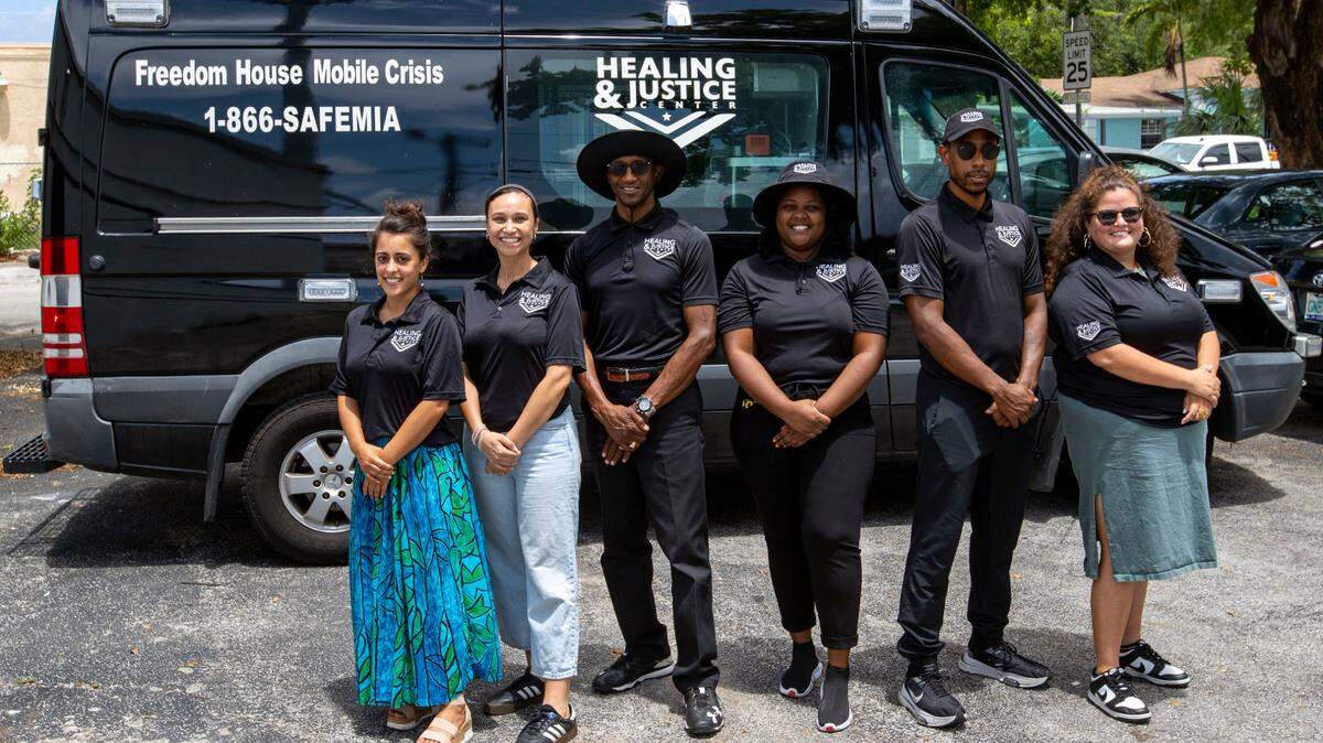 Members of the Healing and Justice Center stand in front of the Freedom House Mobile Crisis Response and Free Urgent Care van in Liberty City.