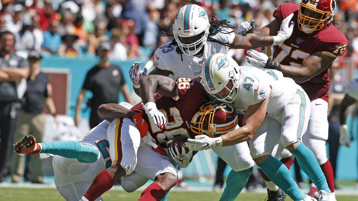 Miami Dolphins defensive end Avery Moss (93), linebacker Vince Biegel (47) and free safety Reshad Jones (20) gang tackle Washington Redskins running back Adrian Peterson (26) in the first quarter as the Miami Dolphins host the Washington Redskins at Hard Rock Stadium in Miami Gardens on Sunday, October 13, 2019.