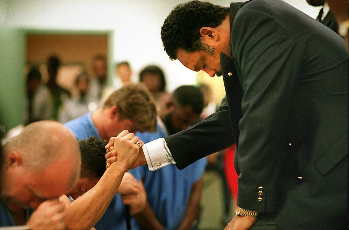 In 1995, the Rev. Jesse Jackson prays with prisoners from the Dade County Stockade. Jackson was touring the new Metro Dade Department of Corrections and Rehabilitation Boot Camp. The military-style boot camp for first time offenders is designed to give prisoners job skills and self-reliance.