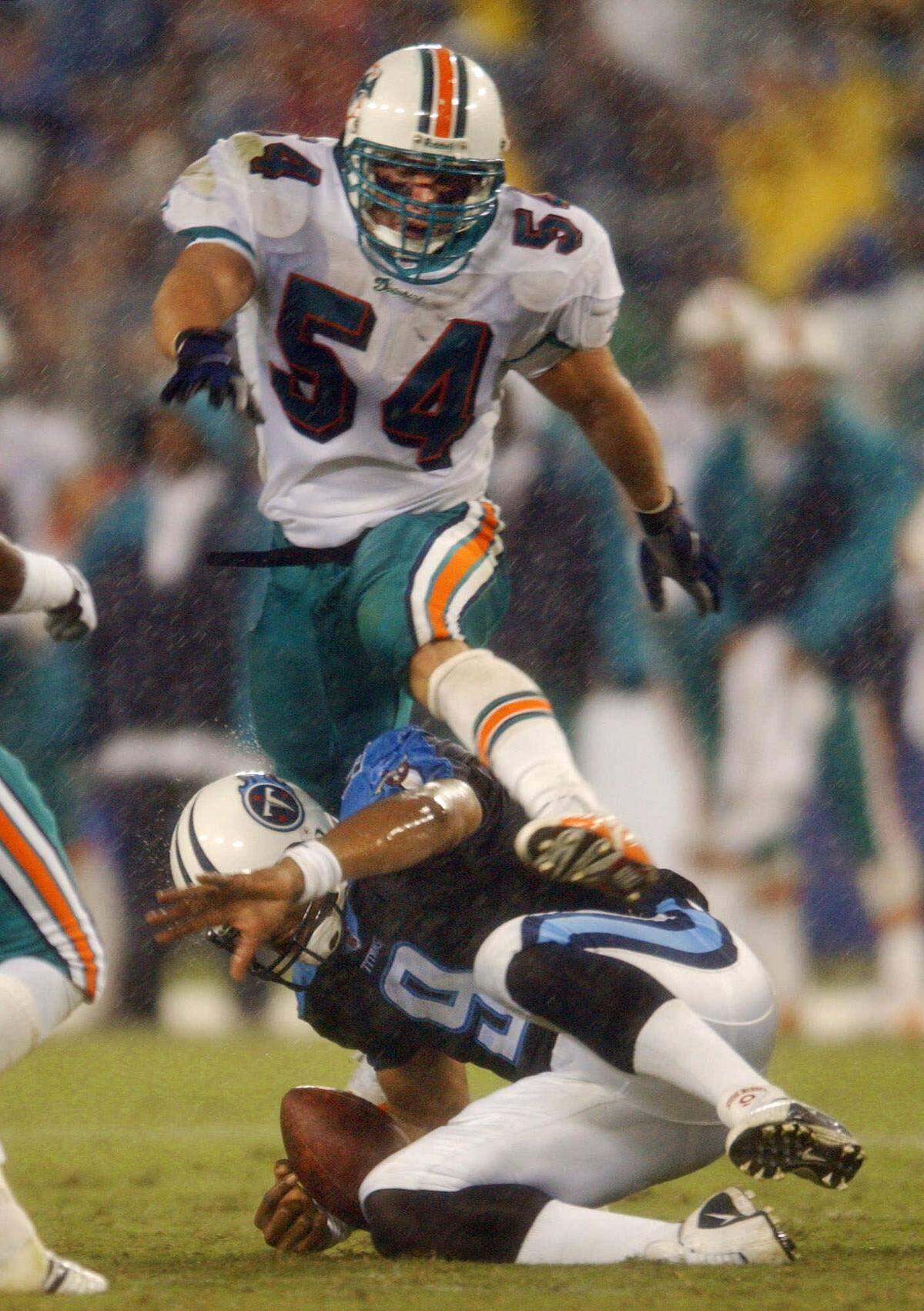Miami Dolphins linebacker Zach Thomas leaps over sliding Tennessee Titans’ quarterback Steve McNair during a 2001 game.