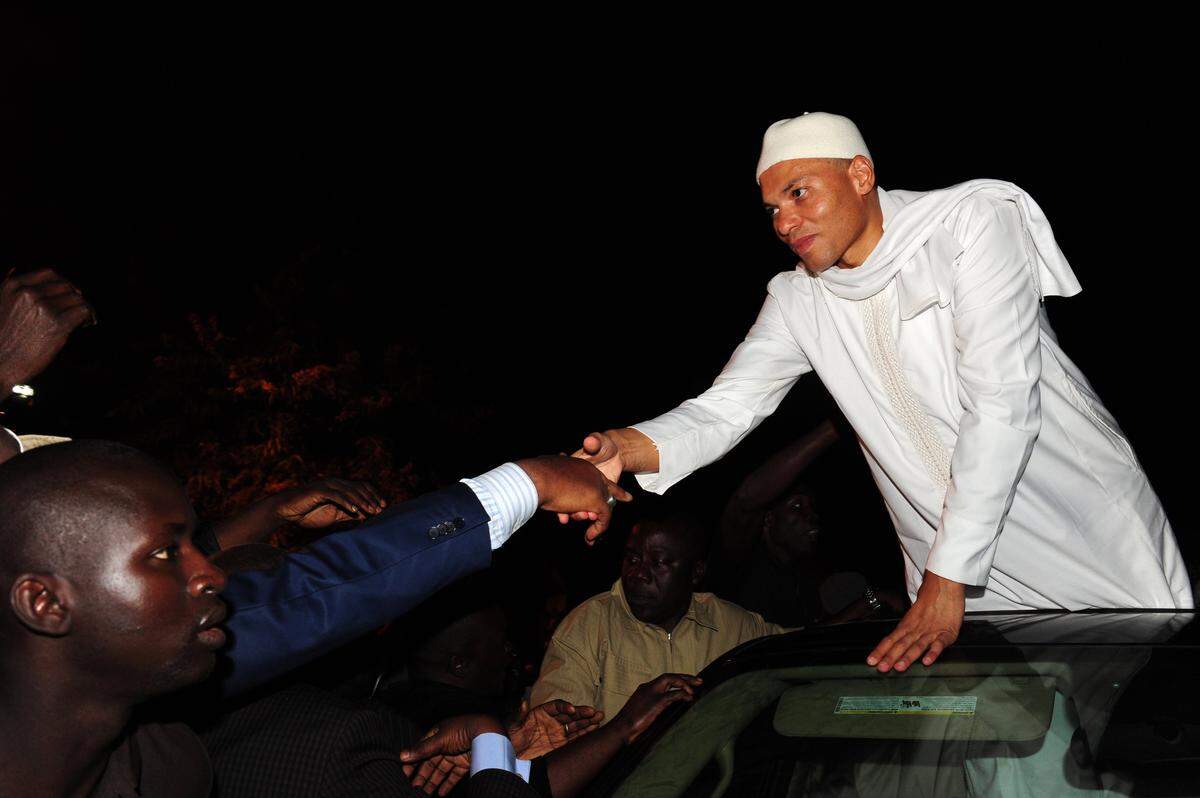 Karim Wade, son of the former President of Senegal Abdoulaye Wade and a former minister in his government, greets supporters as he leaves a police station after questioning, in Colobane, a neighborhood of Dakar, on December 20, 2012. (SEYLLOU/AFP via Getty Images)