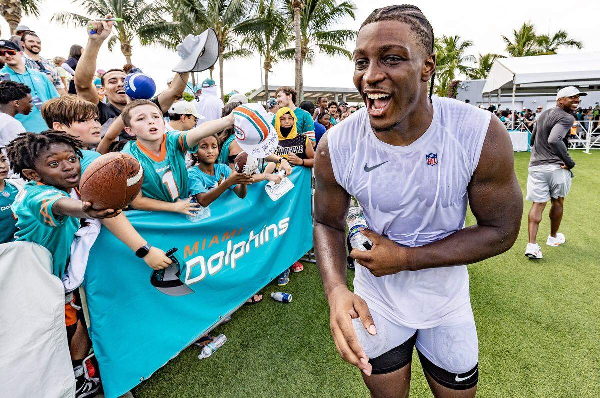 Miami Dolphins linebacker Channing Tindall (41) reacts as fans seek autographs.