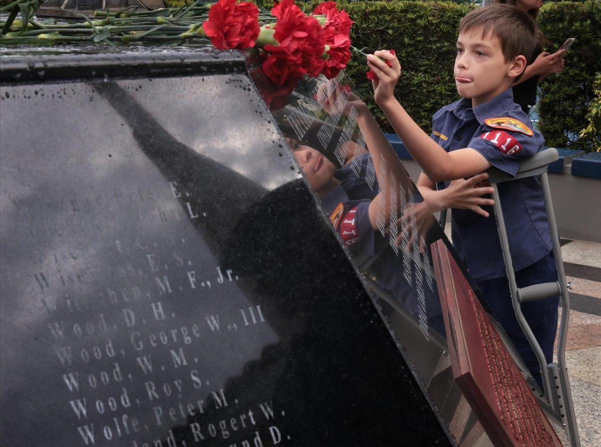 Luca Silva, 10, places a carnation as the names of Coral Gables residents, who died during the Vietnam War in service of their country, are read on Memorial Day on Monday, May 30, 2022. Residents, veterans, families and friends gathered for the City of Coral Gables’ Memorial Day Remembrance Ceremony at the War Memorial Youth Center. The monument, dedicated to fallen Coral Gables WW II enlisted military, served as a reflection point. Red carnations were placed on its ledge by the local Boy Scout Troop #7 in honor of Gables residents who died during their service in the Vietnam War.
