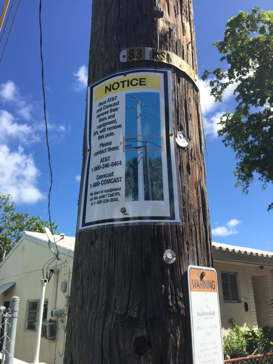 A Florida Power & Light sign says those ugly black canisters that have shown up on Miami trees and swales belong to AT&T.