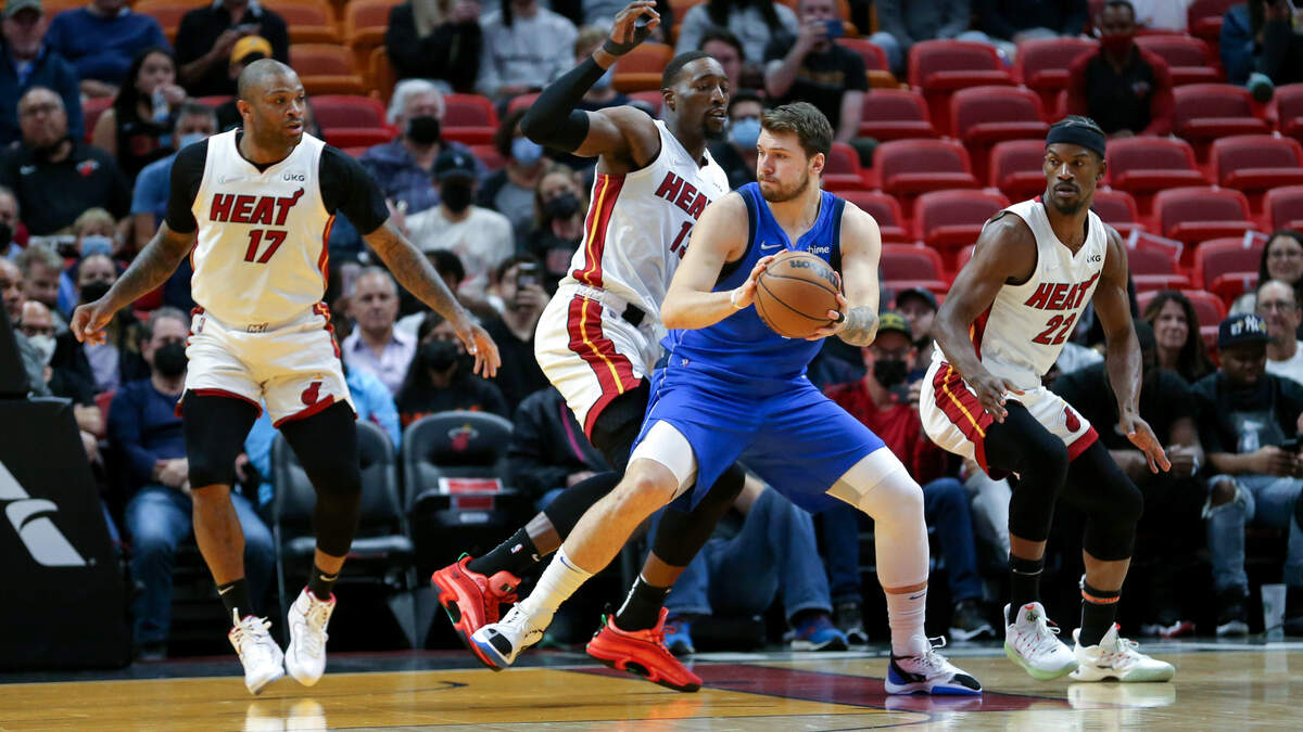 El armador de los Mavericks, Luka Doncic (77), conduce la pelota ante la defensa de los jugadores del Heat, PJ Tucker (17), Bam Adebayo (13) y Jimmy Butler (22), el martes 15 de febrero de 2022 en el FTX Arena de Miami.