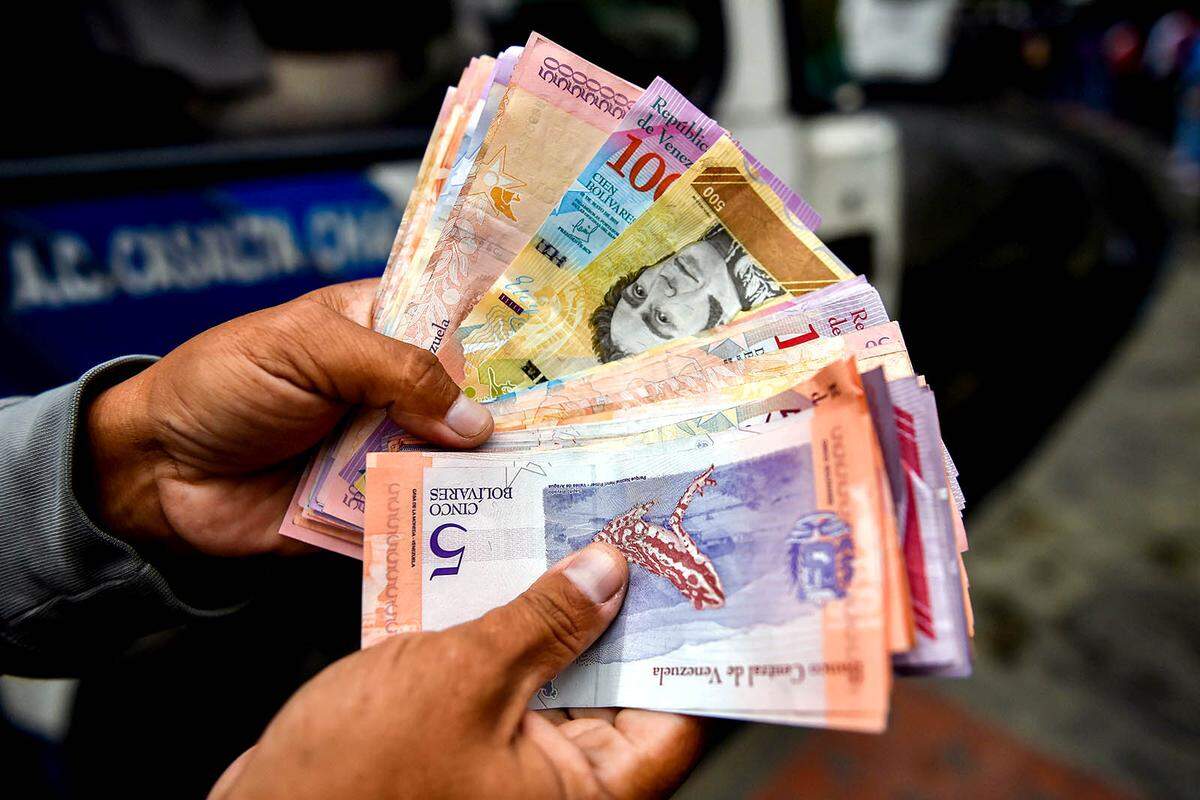 A man counts devalued Bolivar bills on a street in Caracas, Venezuela last year.