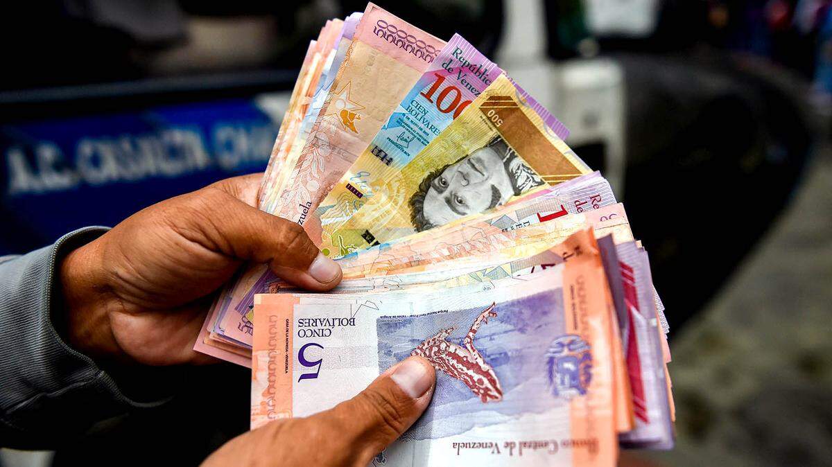 A man counts devalued Bolivar bills on a street in Caracas, Venezuela last year.