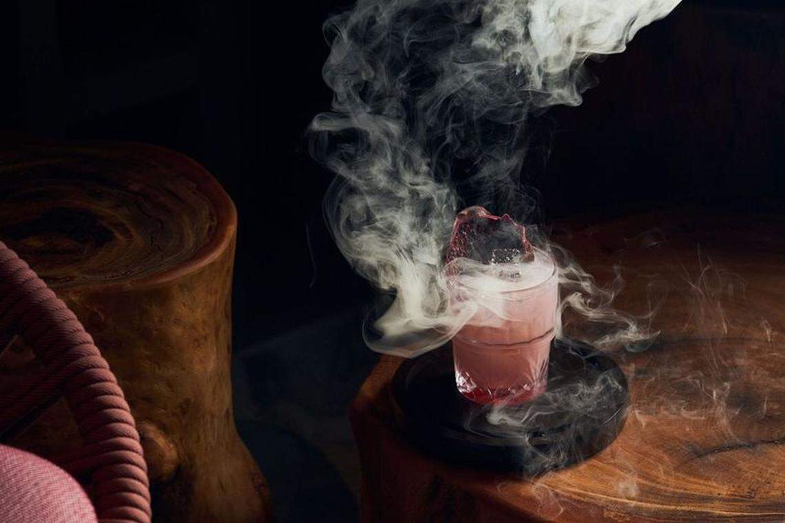 Smoke wafts off of a pink cocktail on a counter at Nubé Rooftop.