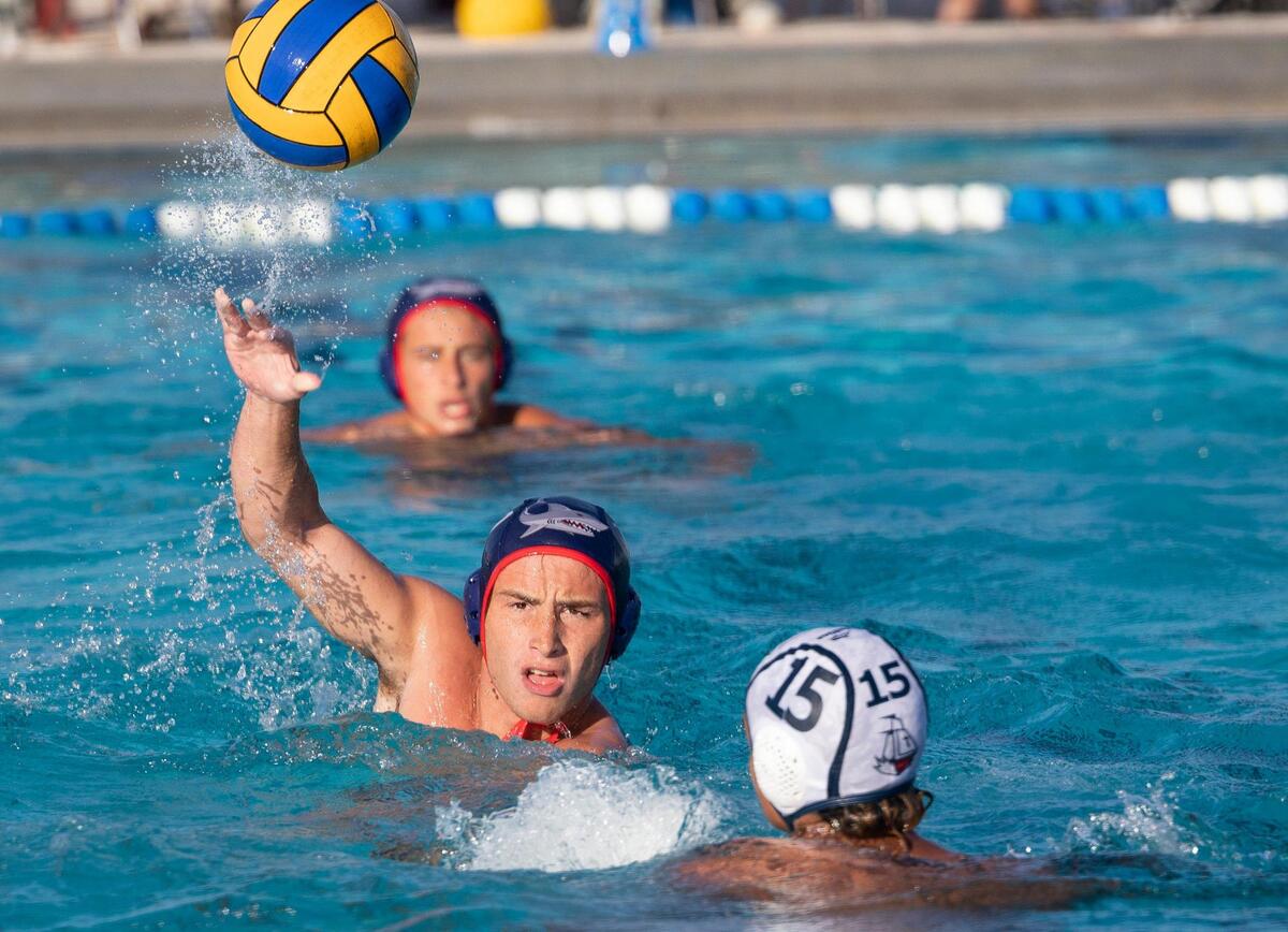 MAST’s Ignacio Rivero (12) throws the ball over Columbus’ Marcos Perez (15) during the first period of the GMAC boys water polo finals on Wednesday, March 20, 2024, at MAST Academy on Virginia Key.