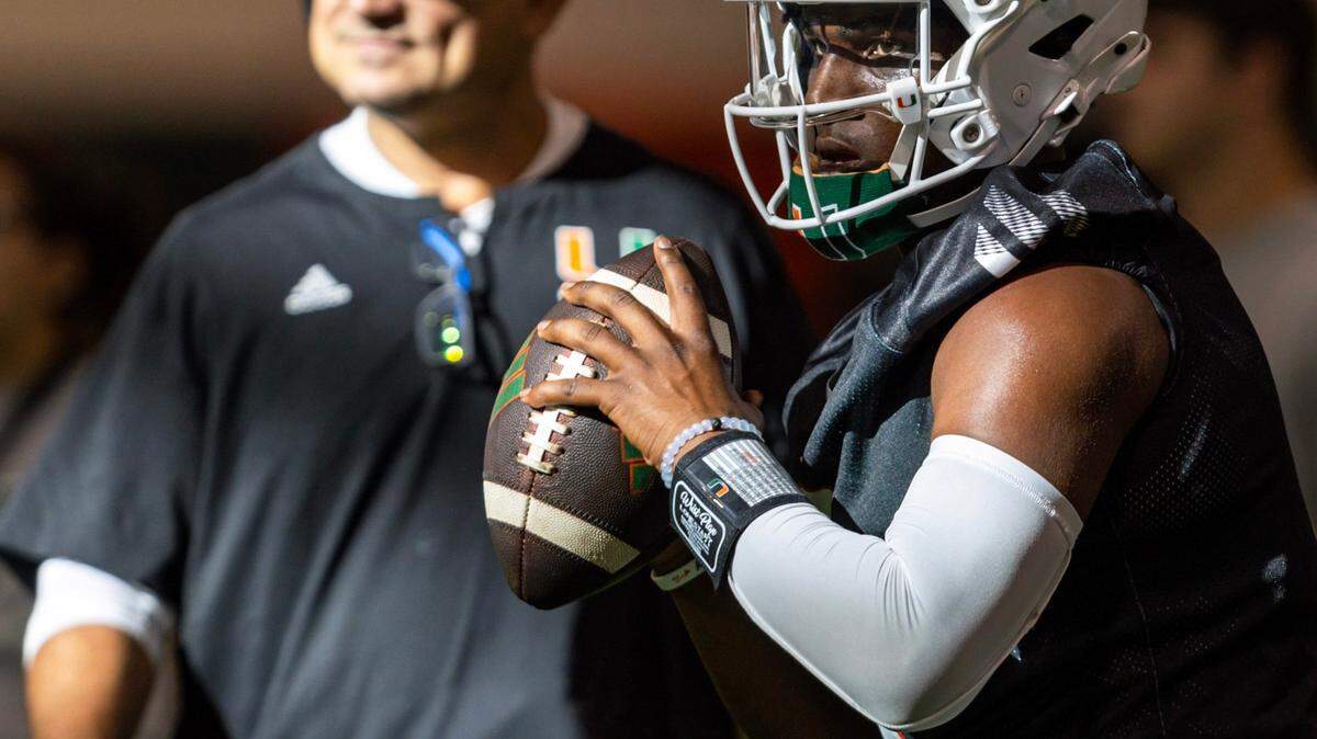 Miami Hurricanes quarterback Cam Ward (1) looks to throw the ball as Offensive Coordinator / Quarterbacks Coach Shannon Dawson looks on at the Carol Soffer Indoor Practice Facility on Wednesday, July 31, 2024, in Coral Gables, Fla.