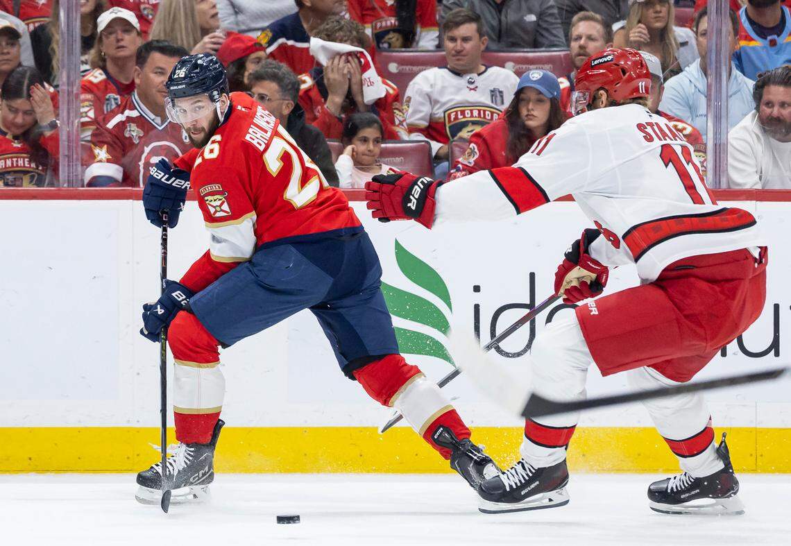 Florida Panthers defenseman Uvis Balinskis (26) passes the puck as Carolina Hurricanes center Jordan Staal (11) defends in the first period of Game 4 during the Eastern Conference final of the NHL Stanley Cup playoffs at Amerant Bank Arena on Monday, May 26, 2025, in Sunrise, Fla.