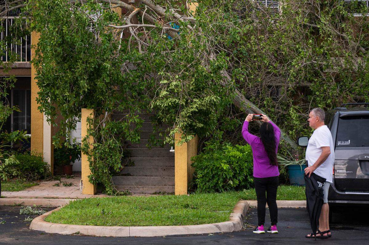 Passers-by photograph tornado damage at the Sanctuary Cove Apartment complex on Sunday, April 30, 2023, in Palm Beach Gardens, Fla. The National Weather Service confirmed an EF-1 tornado touched down in Palm Beach Gardens Saturday evening.