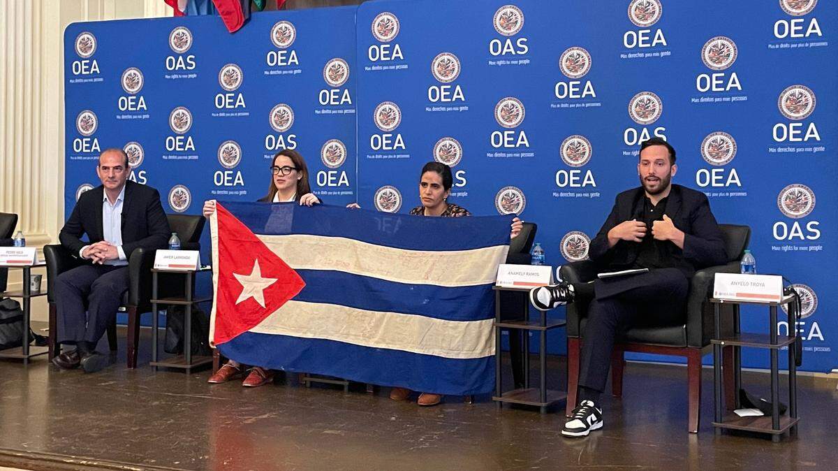Cuban journalist Monica Baró, left, and activist and art professor Anamely Ramos hold a Cuban flag used in the video clip of the song Patria y Vida, Homeland and Life, during an event highlighting human rights violations in Cuba at the OAS headquarters in Washington, D.C., on Tuesday, April 18, 2023.