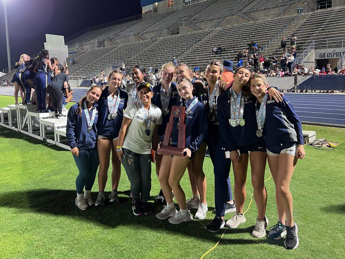 Palmer Trinity’s girls’ track and field athletes and coach Tammy King (left of trophy holder) celebrate their state runner-up finish at the Class 1A state meet on Wednesday night at Hodges Stadium in Jacksonville, Fla.