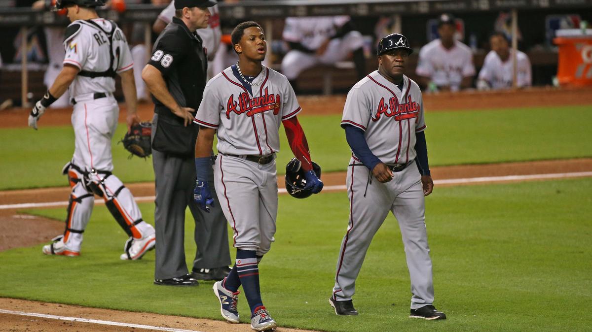 Atlanta Braves left fielder Ronald Acuna Jr. walk to first base with first base coach Eric Young after being hit by a pitch thrown by Miami Marlins pitcher Jarlin Garcia during the sixth inning of a Major League Baseball game at Marlins Park on Thursday, August 23, 2018.